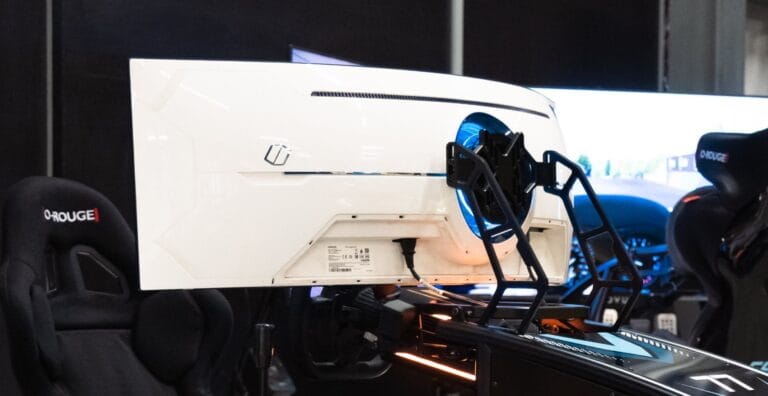 Two racing simulators with triple monitor mounts and bracket systems in professional exhibition setup