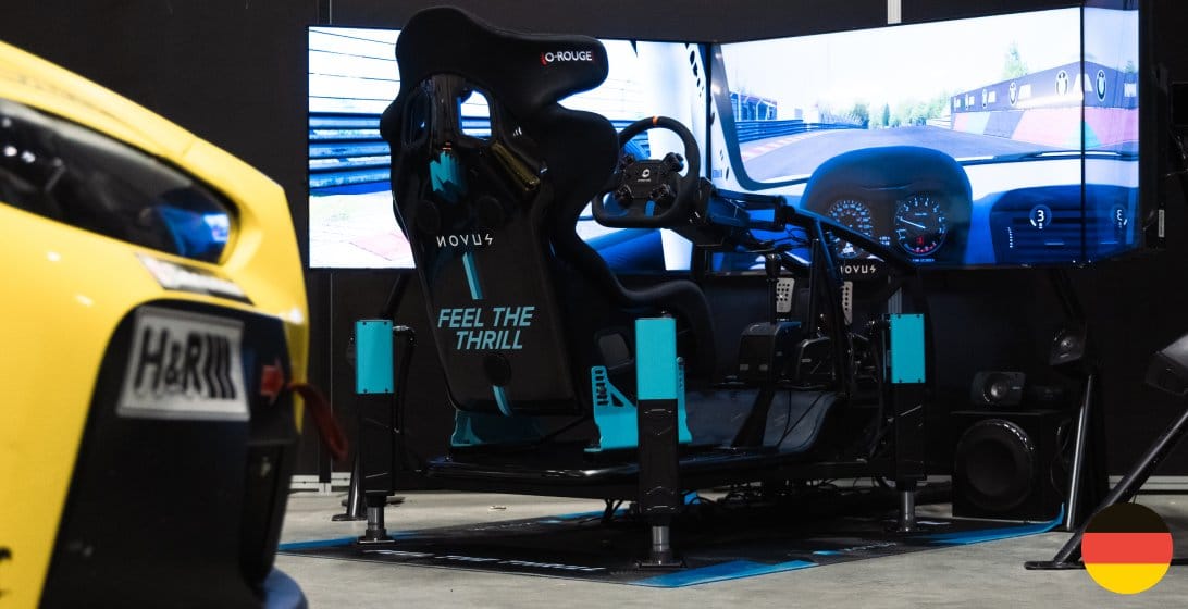 Novus Misha Spec racing simulator with black and cyan X Cage chassis at Vulcan Alpha workshop in Germany for private demonstrations